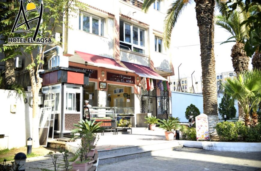 Exterior view of Hotel El Aqsa in Blida city center, showing the hotel building and its urban surroundings.